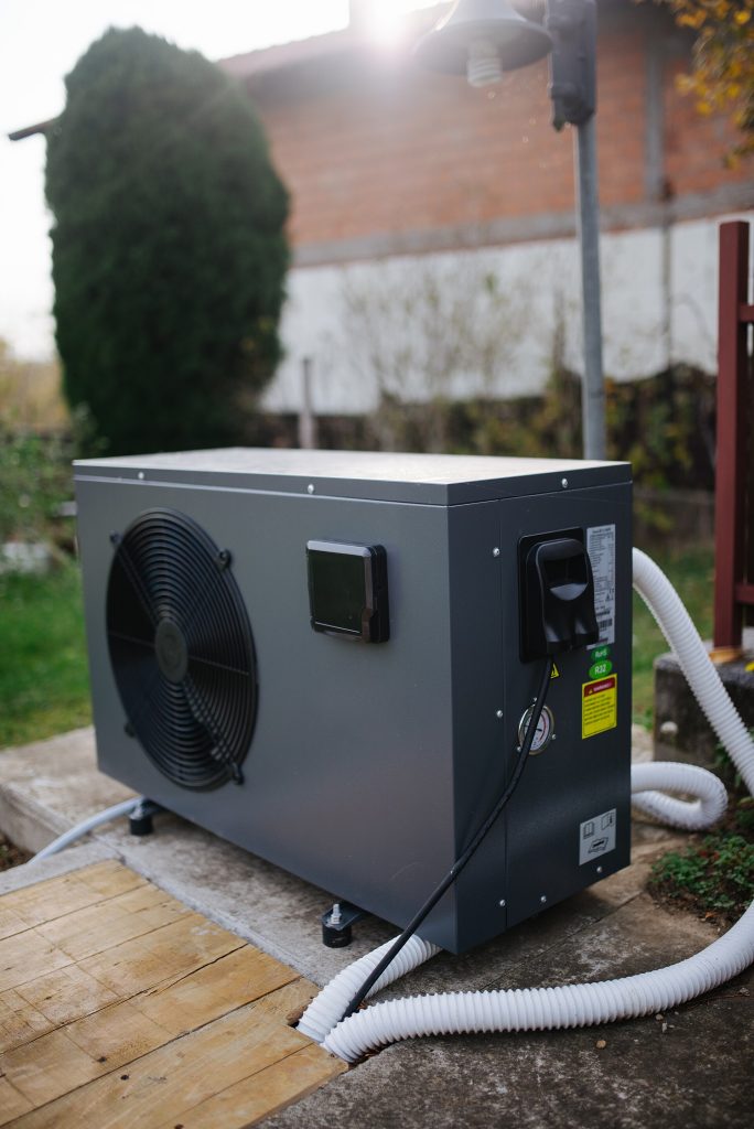 A modern air-source heat pump unit installed outside a family house